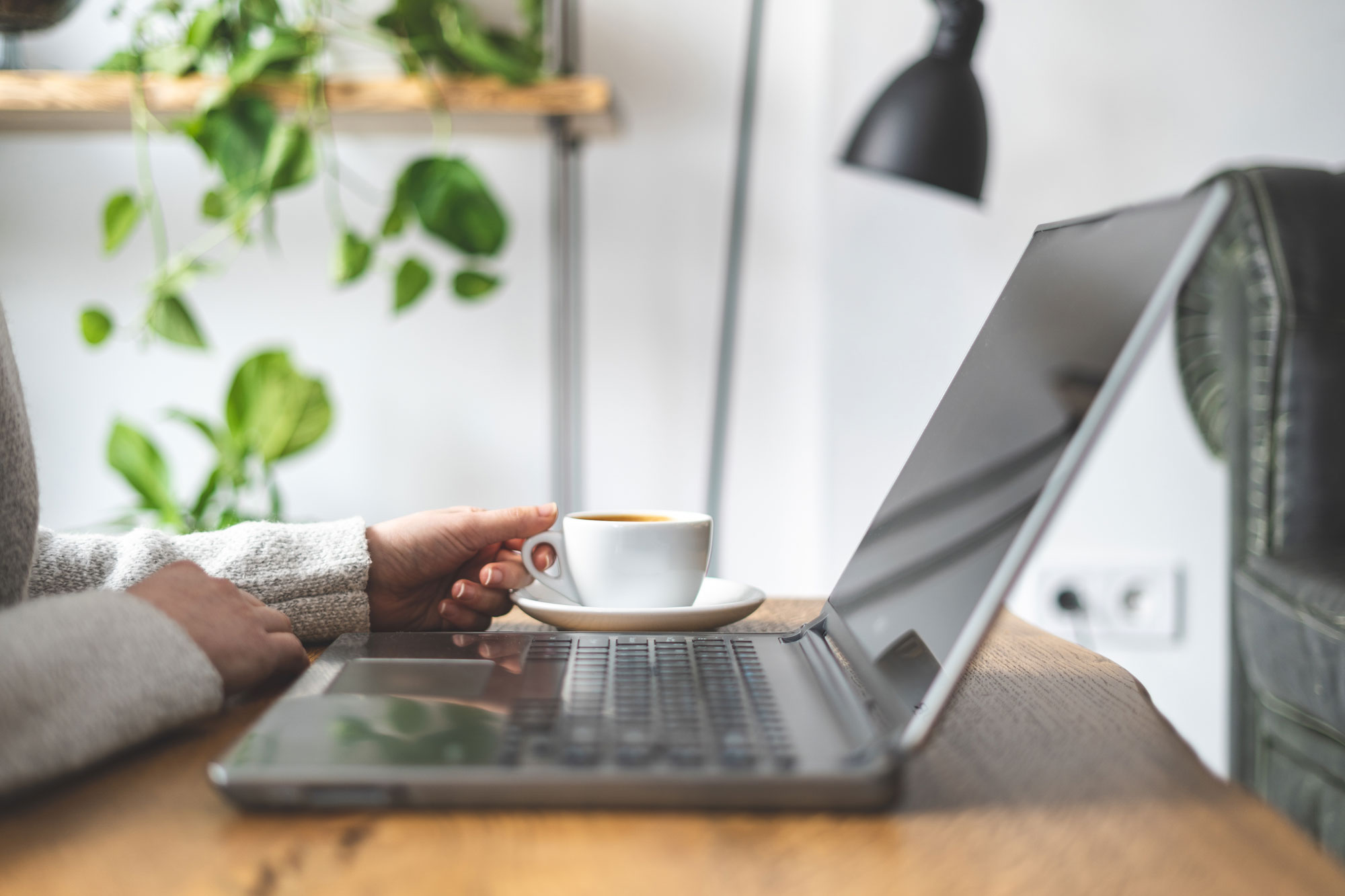 computer on a desk with lady holding a cup